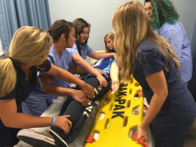 Student placing a mannequin patient on a board.