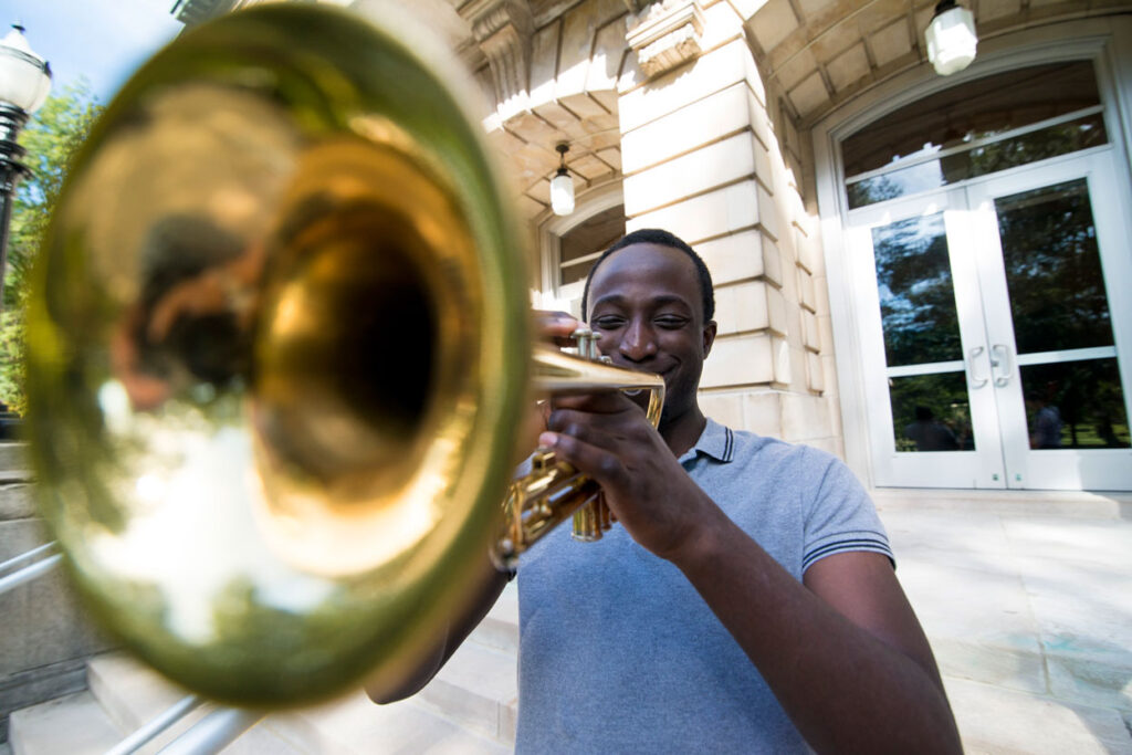 Music student playing trumpet in front of The Conserve